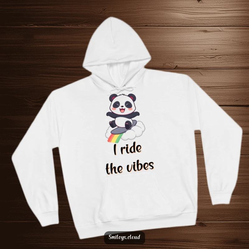 Funny hoodie depicting a cheerful panda surfing majestically on a vibrant rainbow cloud, exuding happiness and adventure.